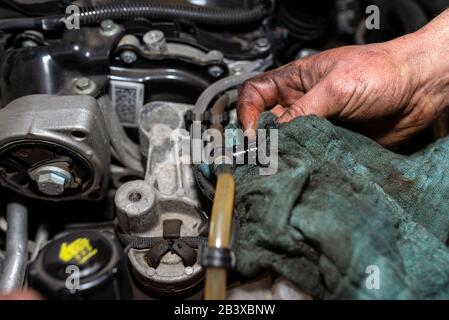 Der Mechaniker entlüftet das Kraftstoffsystem mit einer Pumpe, die sich auf der Kraftstoffleitung befindet. Nach dem Einbau eines neuen Kraftstofffilters sind die Hände des Mannes sichtbar. Stockfoto