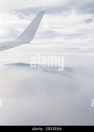 Flugzeugflügel auf dem Himmelshintergrund, der über der Insel fliegt. Bild auf Handy gemacht Stockfoto