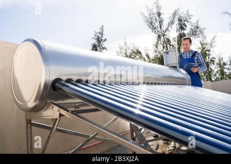 Klempner, Der Die Prüfung Des Solar-Energiekessels Durchgeführt Hat Stockfoto