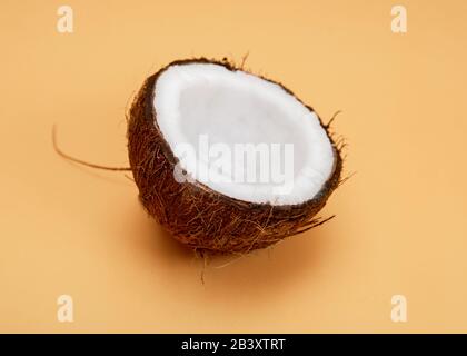 Frische halbe natürliche Kokosnuss auf orangefarbenem Hintergrund. Stockfoto