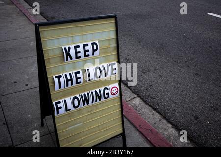 Bewegliches Typenschild auf dem Gehweg sagt "Keep the Love Flowing" Stockfoto