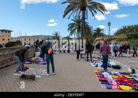 Palma, Mallorca - 10. April 2019: Afrikanische Straßenhändler versuchen, Piraterie auf Touristen in der Nähe der Kathedrale de Palama zu verstauen Stockfoto