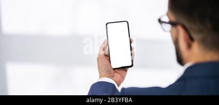 Nahaufnahme der Person Hände halten Handy Mit Leerer Bildschirm am Schreibtisch Stockfoto
