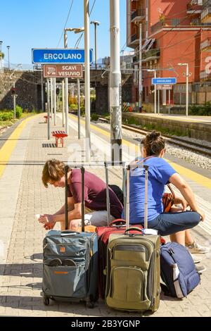 Ercolano, IN DER NÄHE VON NEAPEL, ITALIEN - AUGUST 2019: Gruppe junger Leute mit Gepäck, die auf einen Zug am Bahnhof Ercolano in der Nähe von Neapel warten Stockfoto