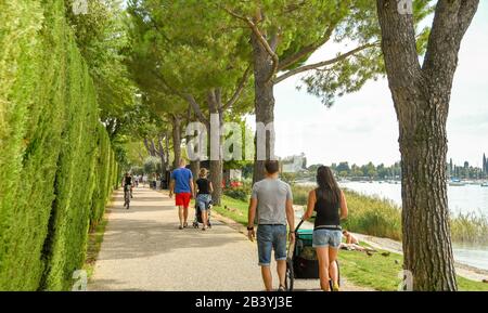 Auf DER STRECKE GARDA NACH BARDOLINO, GARDASEE, ITALIEN - SEPTEMBER 2018: Menschen, die auf dem Weg um den Gardasee von Garda nach Bardolino spazieren Stockfoto
