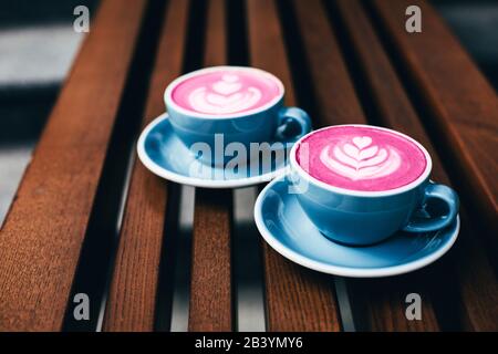 Zwei trendige Rote Beete lattes mit Latte Art und Blütenblätter auf den Schaum. Stockfoto