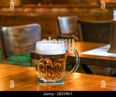 Prag, TSCHECHIEN - JULI 2018: Glas schäumendes tschechisches Pilsner lager-Bier auf einem Holztisch in einer Bar in Prag Stockfoto