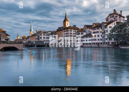 Berühmte Fraumunster und Peterskirche mit Reflexionen in der Limmat bei Sonnenaufgang in Der Altstadt von Zürich, der größten Stadt der Schweiz Stockfoto