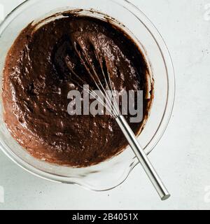 Schokoladen-Teig, bereit zum Backen in einer Glasschale mit einem Schneebesen Stockfoto