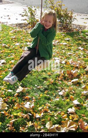 Ein kleines Mädchen hält sich beim Seilschwingen fest. Stockfoto