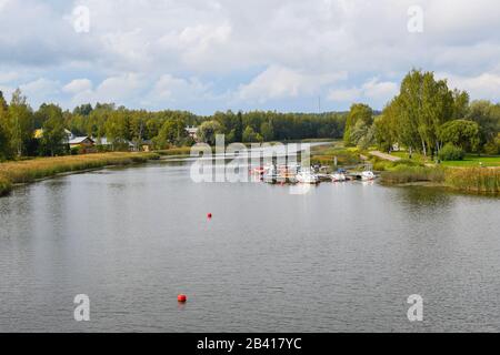 A cloudy early autumn day with boats, dock, homes and a park along the Porvoonjoki River in Porvoo, Finland. Stockfoto