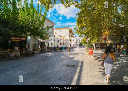 Touristen wandern vorbei an Cafés und Souvenirläden in der touristischen Innenstadt der antiken Stadt Olympia Griechenland. Stockfoto