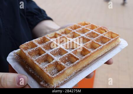 Nahaufnahme einer belgischen Waffel mit Puderzuckerpulver. Tourist in Belgien mit einer authentischen Waffel Stockfoto