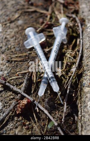 Gebrauchte Nadeln, die in einem öffentlichen Park entsorgt wurden. Opioidkrisenverschmutzung. Gefahr ansteckender Krankheiten Stockfoto