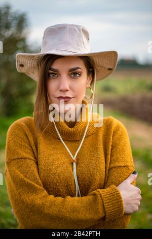 Hübsches Frauenporträt mit einem Hut neben Erdfeldern Stockfoto