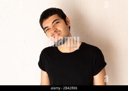 Junger kurzhaariger hispanischer Mann mit schwarzer Kleidung, wütend, wütend, verärgert, gestresst, auf weißem Hintergrund posiert Stockfoto