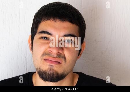 Junger kurzhaariger hispanischer Mann mit schwarzer Kleidung, wütend, wütend, verärgert, gestresst, auf weißem Hintergrund posiert Stockfoto