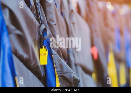 Eine gelbe Pfeife mit schwarzer Lebensjacke, die am Geländer um den Gehweg hängt, damit die Passagiere sicher an den Docks sind. Stockfoto