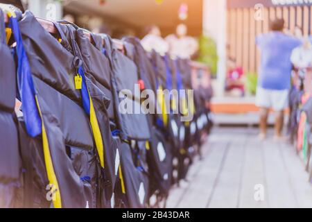 Eine gelbe Pfeife mit schwarzer Lebensjacke, die am Geländer um den Gehweg hängt, damit die Passagiere sicher an den Docks sind. Stockfoto