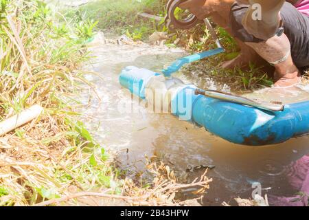 Defektes Rohr in Bohrung mit Wasserbewegung am Straßenrand und Installateur Reparatur- und Sicherungszange Stockfoto