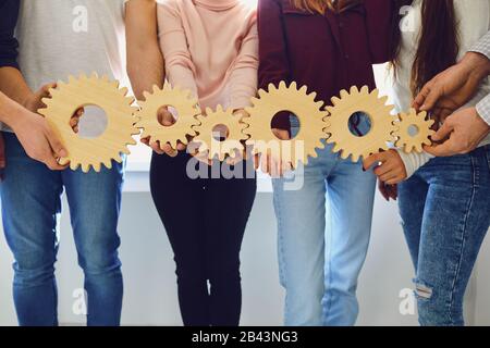 Die Hände von Menschen halten Holzzahnräder in Innenräumen. Stockfoto