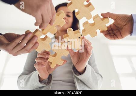 Gesichtslose Geschäftsleute, die Puzzleidee zusammenlegen Stockfoto