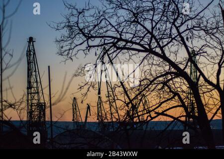 Cargo Krane Silhouetten gegen den dramatischen blauen und orangen Sonnenuntergang Himmel, Warna, Bulgarien, Kran im Hafen Stockfoto