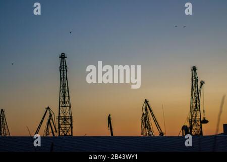 Cargo Krane Silhouetten gegen den dramatischen blauen und orangen Sonnenuntergang Himmel, Warna, Bulgarien, Kran im Hafen Stockfoto