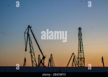 Cargo Krane Silhouetten gegen den dramatischen blauen und orangen Sonnenuntergang Himmel, Warna, Bulgarien, Kran im Hafen Stockfoto