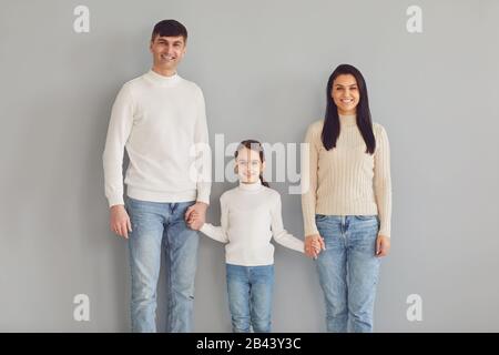 Fröhliche Familie lächelt, während sie vor grauem Hintergrund steht. Stockfoto