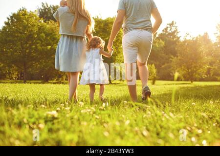 Fröhliche Familienspaziergänge auf dem Gras im Sommerpark. Mutter Vater und Kinder, die in der Natur spielen. Stockfoto