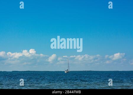 Segelboot mit klarem bewölktem Himmel durch den Ozean. Stockfoto