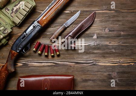 Jagdgewehr und Munition auf dunklem Holzhintergrund.Draufsicht., Jagdgewehr und Munition auf dunklem Holzhintergrund.Draufsicht. Stockfoto