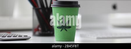 Grüner Kaffee Tasse mit Cannabis Logo auf Office Tabl Stockfoto