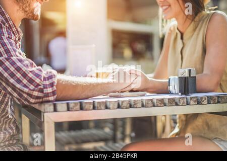Junge Paare halten sich gegenseitig Hände im Café - Zwei Liebhaber sitzen und toben Bier im Café-Restaurant - Love and Travel Concept - Soft Focus Stockfoto
