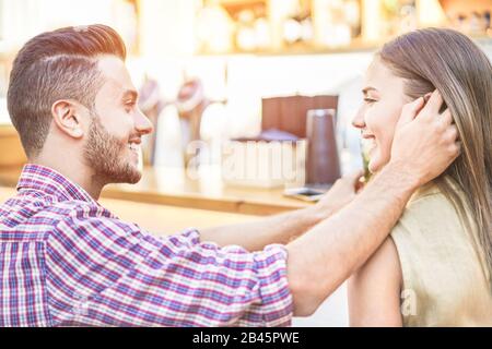 Fröhliches junges Paar mit zarten Momenten und Cocktails in der Lounge-Bar - tausendjährige Liebhaber, die sich auf der Sommerparty unterhalten - Beziehung, Liebe und Stockfoto