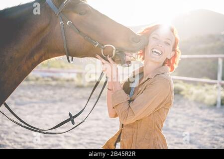 Junge Bauernfrau spielt mit ihrem Pferd an einem sonnigen Tag auf der Korralranch - Konzept über Liebe zwischen Menschen und Tieren - Konzentriert sich auf das Gesicht des Mädchens Stockfoto