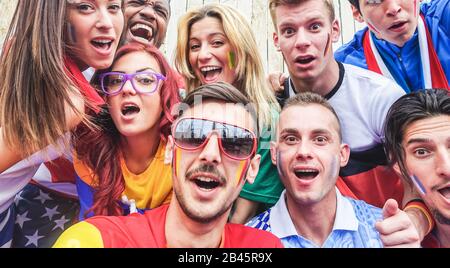 Fröhliche Sportfans, die während des Fußballweltspiels Spaß haben - Junge Fans im Stadion vor dem Fußballspiel - Freundschaft, Jugend und gegen Rassismus Konz Stockfoto