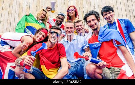 Fröhliche Sportanhänger haben Spaß beim Fußball-Weltspiel - Junge Fans im Stadion vor dem Fußballspiel mit Lufthorn, Fahnen und Megafon - Friendsh Stockfoto