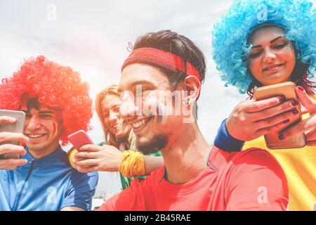 Glückliche Anhänger aus verschiedenen Ländern, die Fußball auf Smartphones online Sport App ansehen - Fokus auf das rechte Gesicht des Mannes - verrückter Fan genießt Weltsoccia Stockfoto