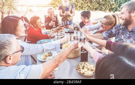 Fröhliche Familie jubelt mit Wein beim Grillabendessen im Freien, während der Vater des Flusspferdes Foto macht - Anderes Alter der Leute, die Spaß am sonntagmenü haben - Foo Stockfoto