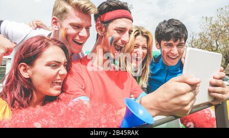 Glückliche Anhänger aus verschiedenen Ländern, die Fußballsport auf einem Notebook-Tablet-PC verfolgen - Hauptaugenmerk auf linke Jungs - verrückter Fan feiert ein Ziel Stockfoto