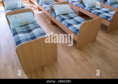 Viele kleine Betten mit frischer Bettwäsche in der Kindertagesstätte Vorschule leere Schlafzimmer Innenraum für komfortable Mittagsschlaf der Kinder. Stockfoto