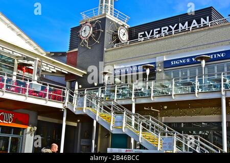 Stufen führen zu Restaurants im ersten Stock mit Blick auf die Cardiff Bay. Auch Everyman Cinema.kunstvolle Uhr als dekoratives Merkmal. Stockfoto