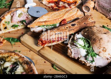 Verschiedene Sandwiches und Pizzabäckchen auf Holztisch. Menü Restaurant. Mediterrane Küche Stockfoto