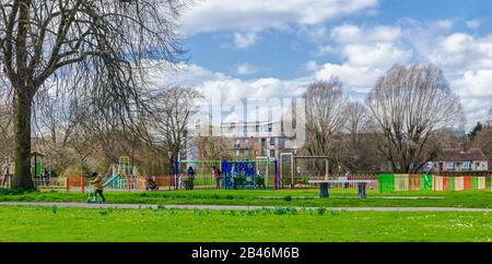 Kinder, die die Spielbereiche im Salt Hill Park, Slough, genießen, während ihre Eltern darauf schauen. Sonniger Tag, Spätwinter. Stockfoto