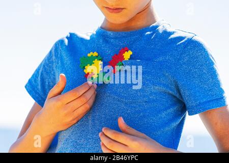 Junge, der buntes Puzzle-Autismus-Bewusstsein in seinen Händen hält Stockfoto