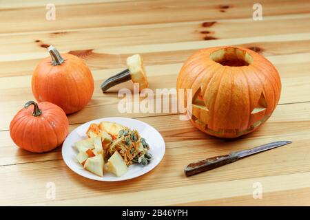 Halloween Schnitzen. Nahaufnahme von Kürbissen oder Jack-o-Laterne und Messer zu Hause. Dekoration und Urlaub Konzept Stockfoto