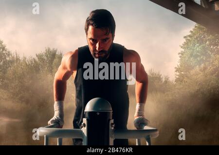 Anstrengung, Schweiß, Staub - kein Schmerz kein Gewinn, Sportler am Bartraining durch Anheben im Freien Stockfoto