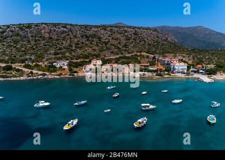 Luftbild mit Blick auf kleine traditionelle Fischerboote im tropischen smaragdfarbenen und türkisfarbenen Meer. Peloponnes, Griechenland Stockfoto